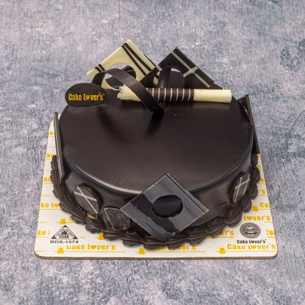 Black cake with decorative elements on a gray surface, branded 'Cake Lover's'.